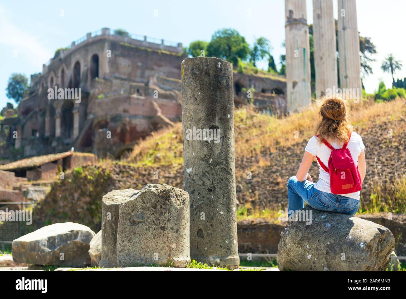 Young female tourist rests on the ruins of the Roman Forum in Rome, Italy Stock Photo