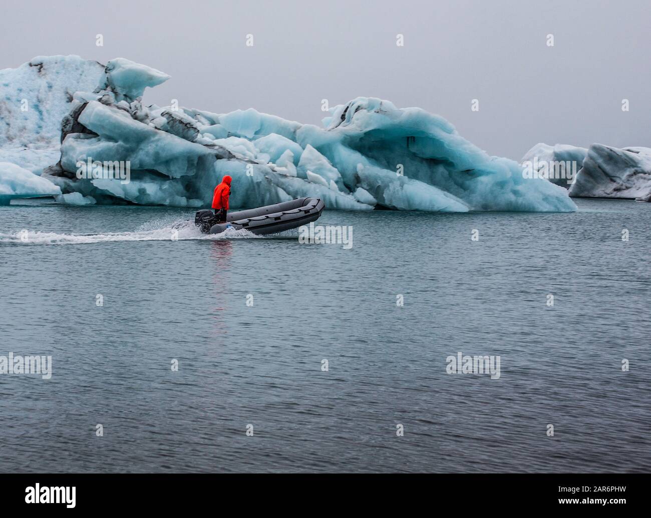 Man with red jacket on a motorized zodiac tour boat, pontoon, raft, Iceland, Europe  Jokulsarlon Glacier Lagoon, East Iceland ice diamond beach Stock Photo