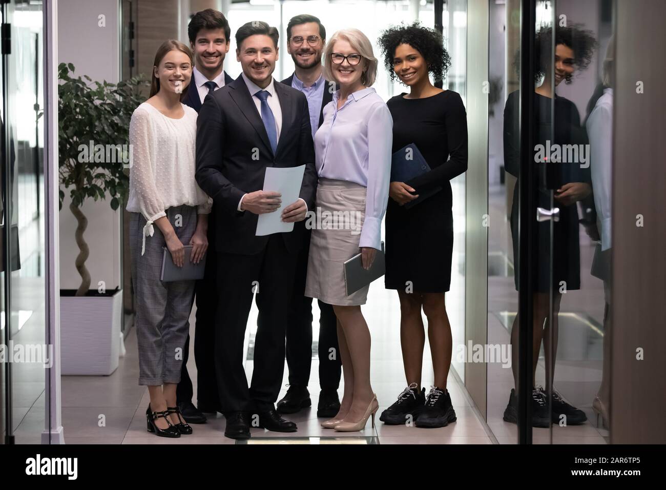Happy multiracial older and younger business people looking at camera. Stock Photo
