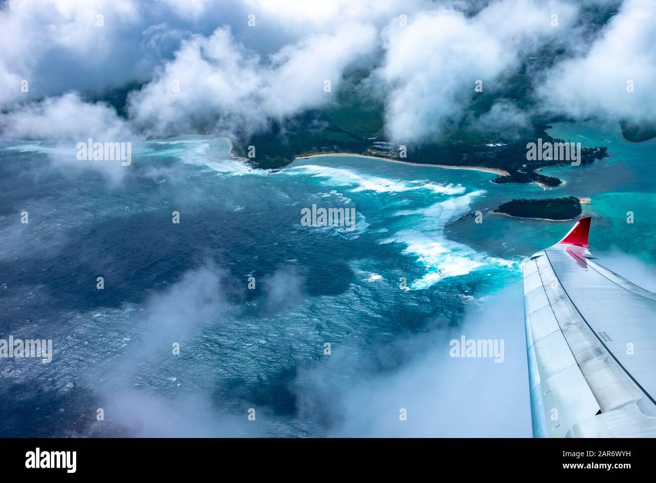 An aerial view of the coastline of Mauritius, in the Indian Ocean, showing the wingtip and colours of an Air Mauritius plane. Stock Photo