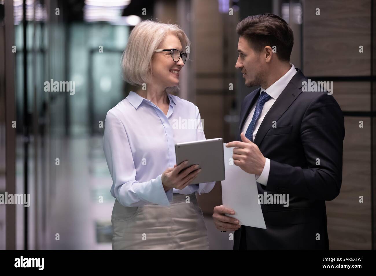 Happy different ages workers discussing working issues in corridor. Stock Photo