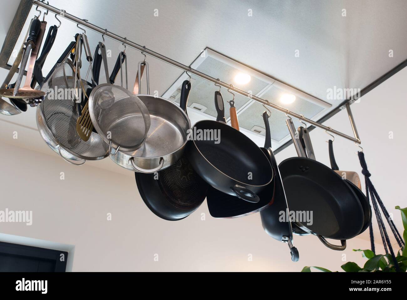 Stainless steel cookware , kitchenware set hanging on a rack on the ...