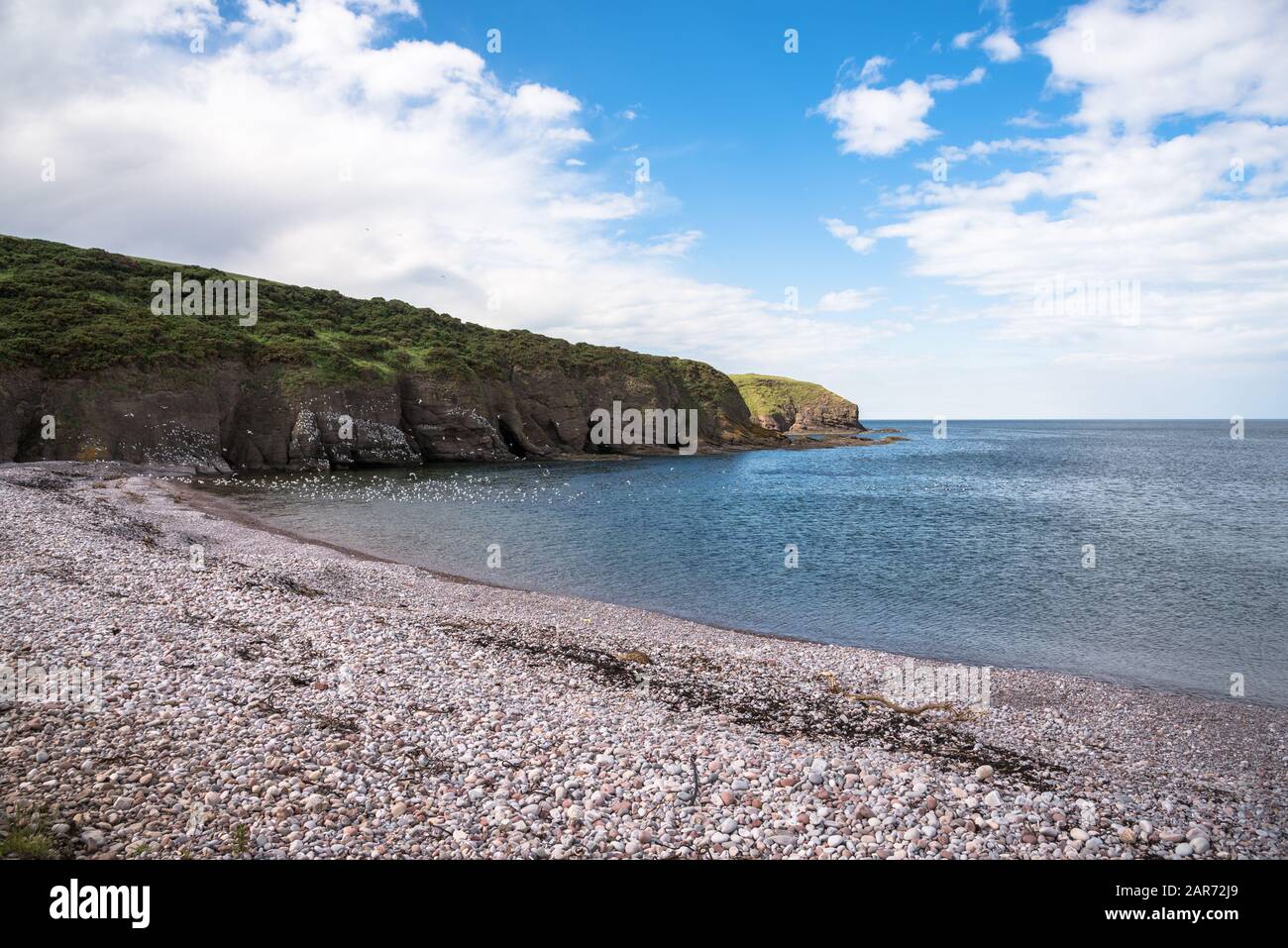 View of a cove vith an empty pebble beach along the west coast of Scotland on a clear spring day Stock Photo