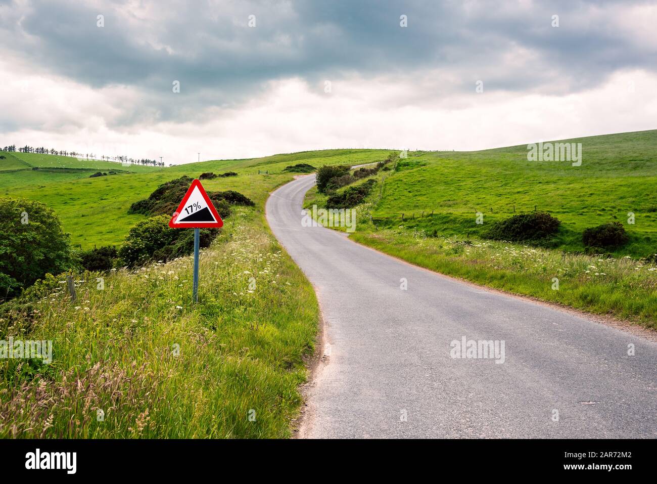 Warning traffic sign along a steep winding road in the Scottish countryside on a cloudy spring day Stock Photo