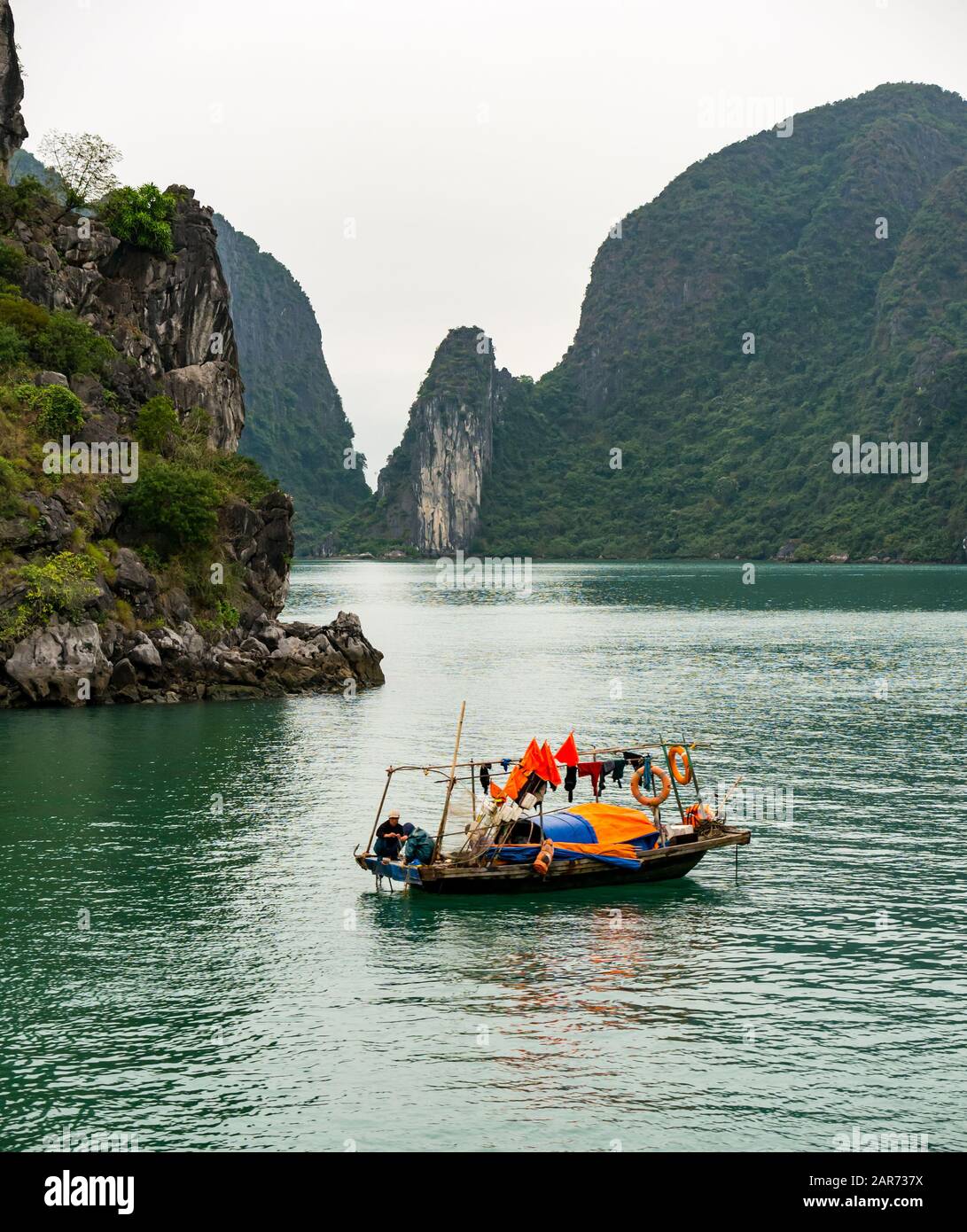 Traditional Vietnamese coracle boat with limestone karst rock formations in foggy weather, Halong Bay, Vietnam, Asia Stock Photo