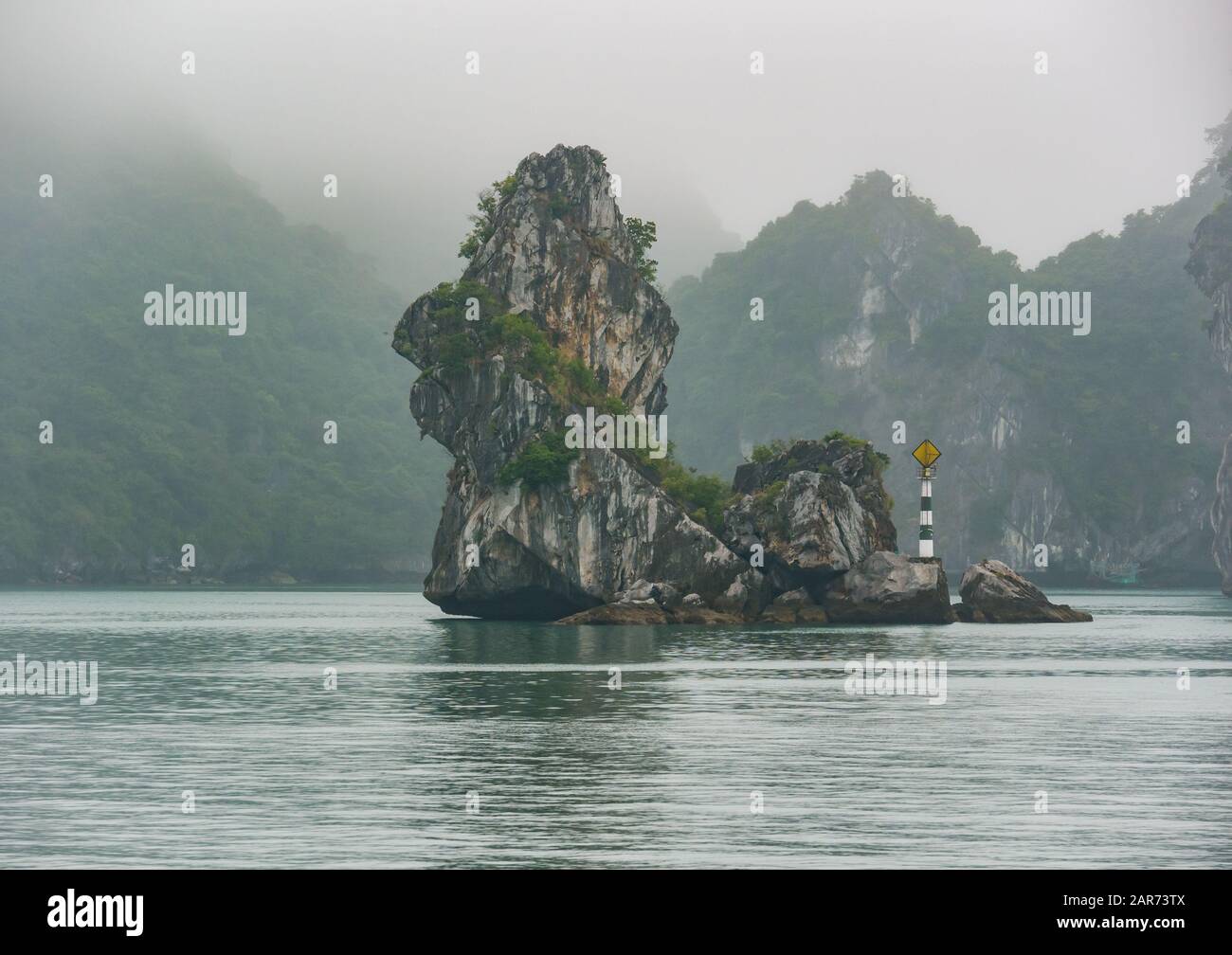 Navigational marker with limestone karst rock formation in foggy weather, Lan Ha Bay, Vietnam, Asia Stock Photo