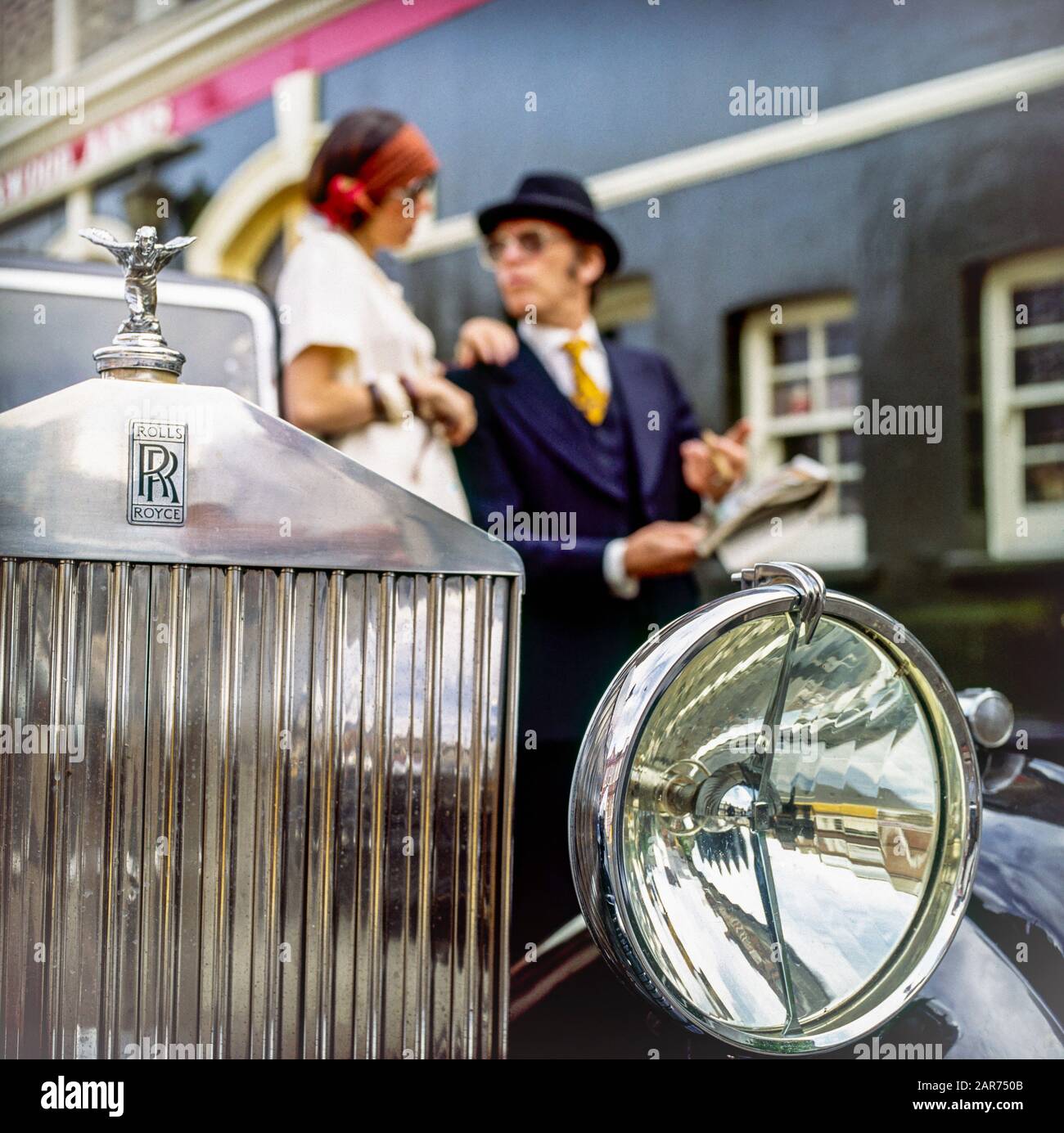 London 1970s, 1936 Rolls-Royce radiator grill, headlight, Spirit of Ecstasy statue, hood ornament, mascot, blurred elegant couple, England, UK, GB, Great Britain, Stock Photo