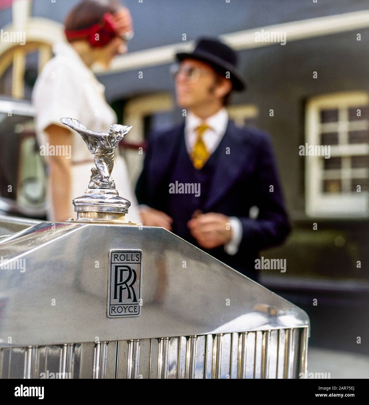 London 1970s, 1936 Rolls-Royce radiator grill, Spirit of Ecstasy statue, hood ornament, mascot, blurred elegant couple, England, UK, GB, Great Britain, Stock Photo