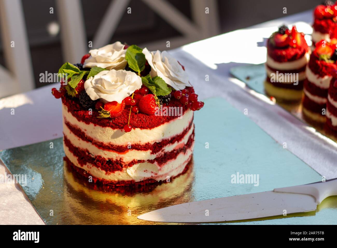 Red velvet cake with close up with white roses and knife Stock Photo