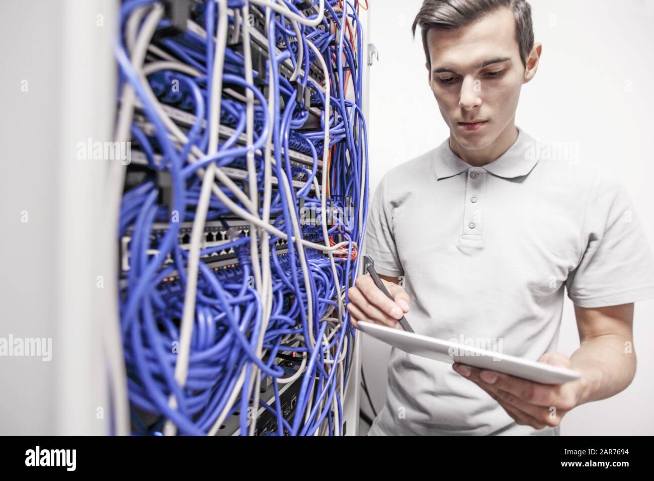 Man using tablet pc beside servers in data center internet technology concept Stock Photo
