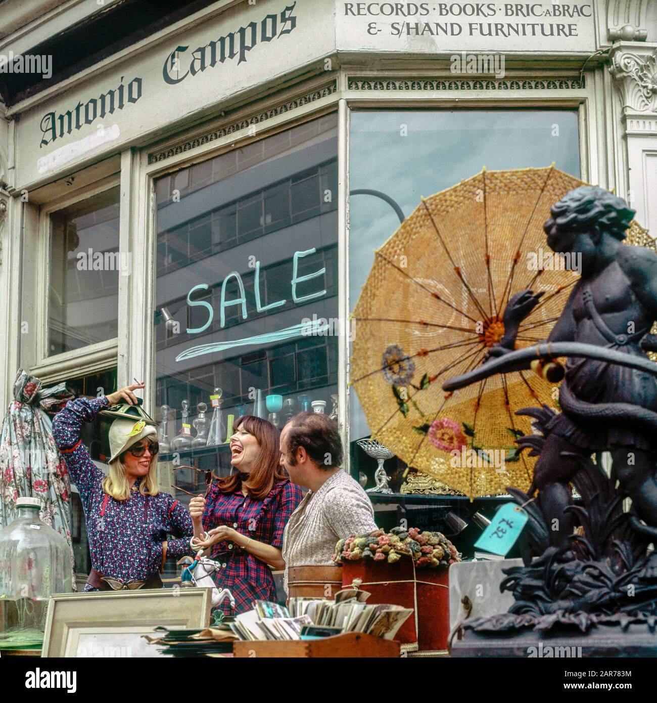 London 1970s, two women having fun with merchant while shopping at antiques store, Kensington, England, UK, GB, Great Britain, Stock Photo
