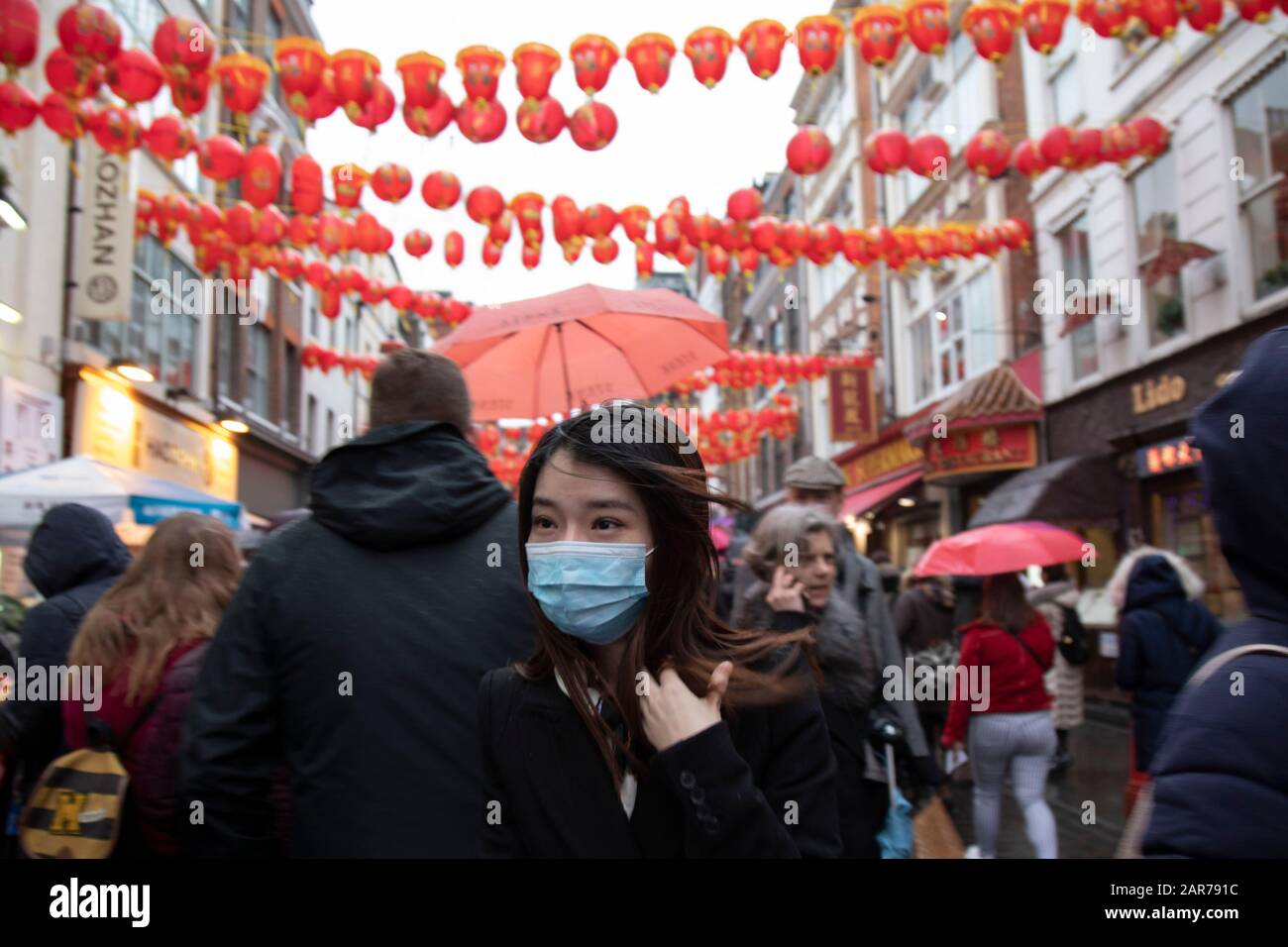 People wearing face masks for Chinese new year celebrations on Gerrard Street in Chinatown on 26th January 2020 in London, England, United Kingdom. Due to the recent coronavirus outbreak an increased number of Chinese / Asian and western people are wearing face masks in public despite NHS Englands advice that the risk of getting the illness in the UK is low. Wuhan novel coronavirus WN-CoV is a new respiratory illness that has not previously been seen in humans. Each year local Chinese community and Londoners gather on this famous area of central London which is the focus of celebrations for th Stock Photo