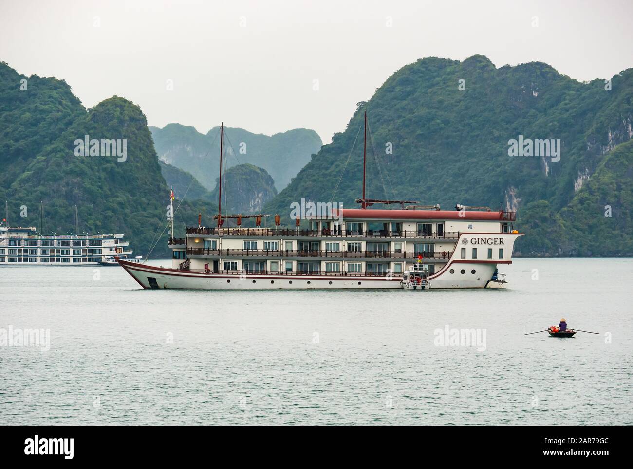 Ginger tourist cruise ship & coracle with limestone karst rock