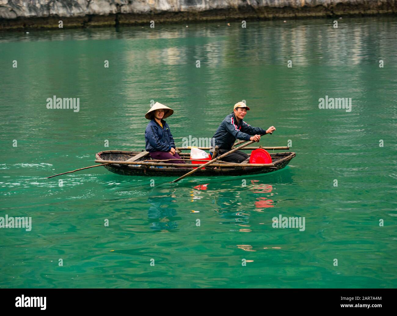 Asian Vietnamese man and woman rowing in coracle, Lan Ha Bay, Vietnam, Asia Stock Photo