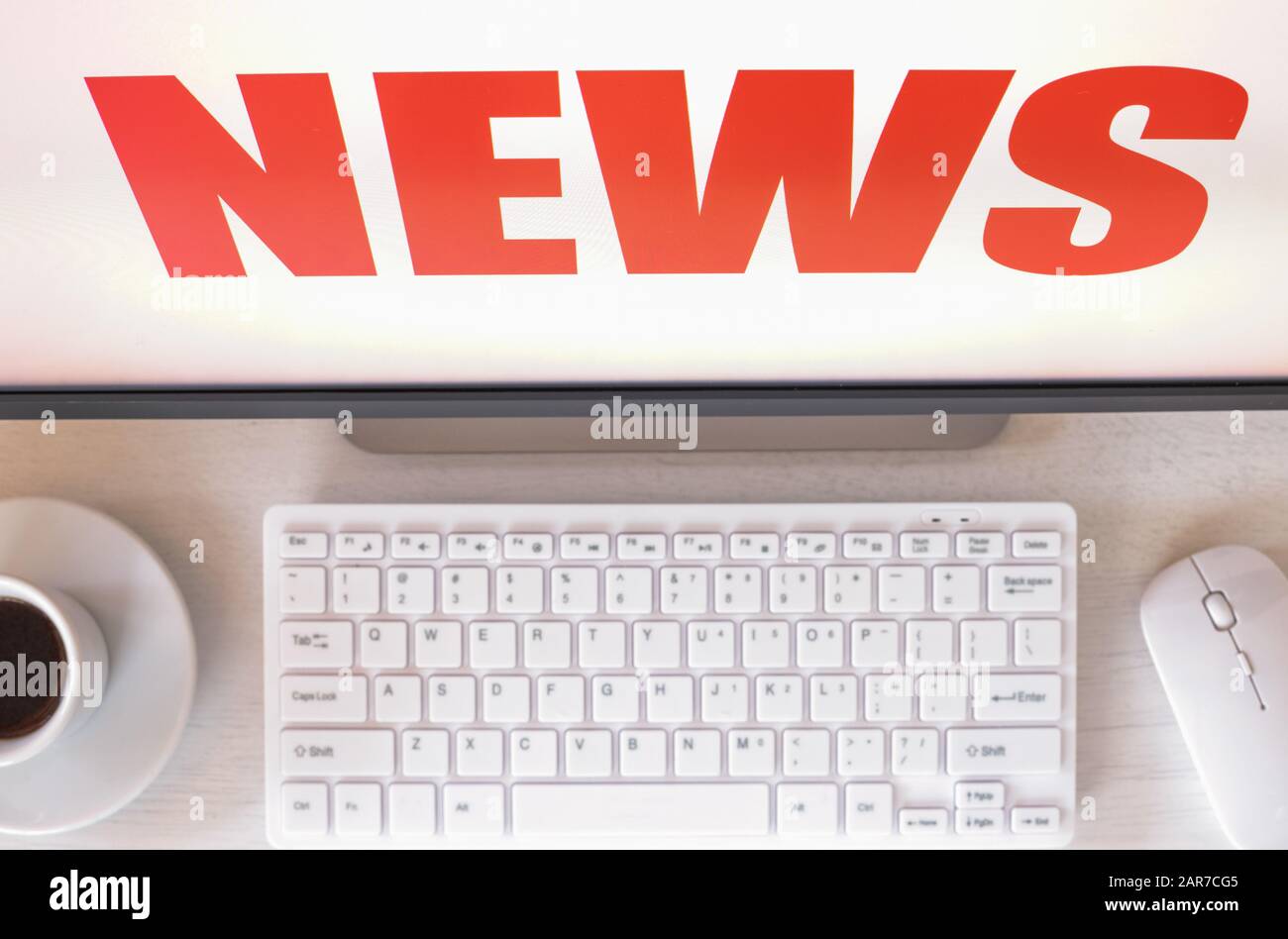 computer monitor with 'News' text displayed Keyboard, mouse, coffee. Concept, sensational news, event, last minute Stock Photo