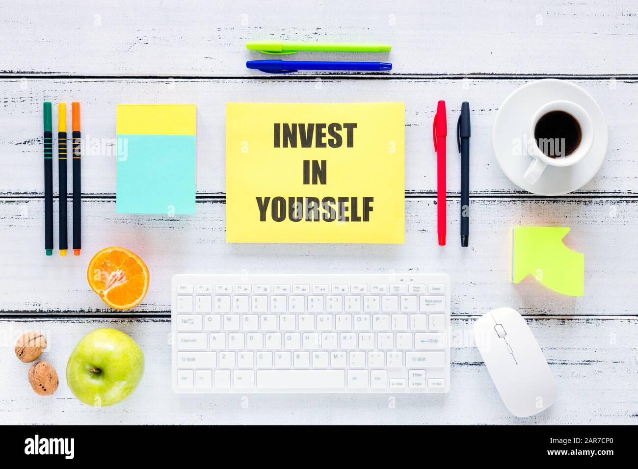A workplace with a large inscription, Invest in Yourself. The concept of personal or business development and self-fulfillment. Keyboard, pens, health Stock Photo