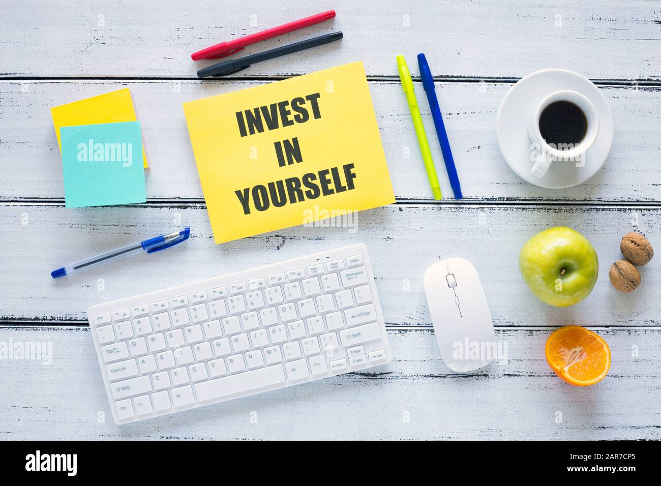 A workplace with a large inscription, Invest in Yourself. The concept of personal or business development and self-fulfillment. Keyboard, pens, health Stock Photo