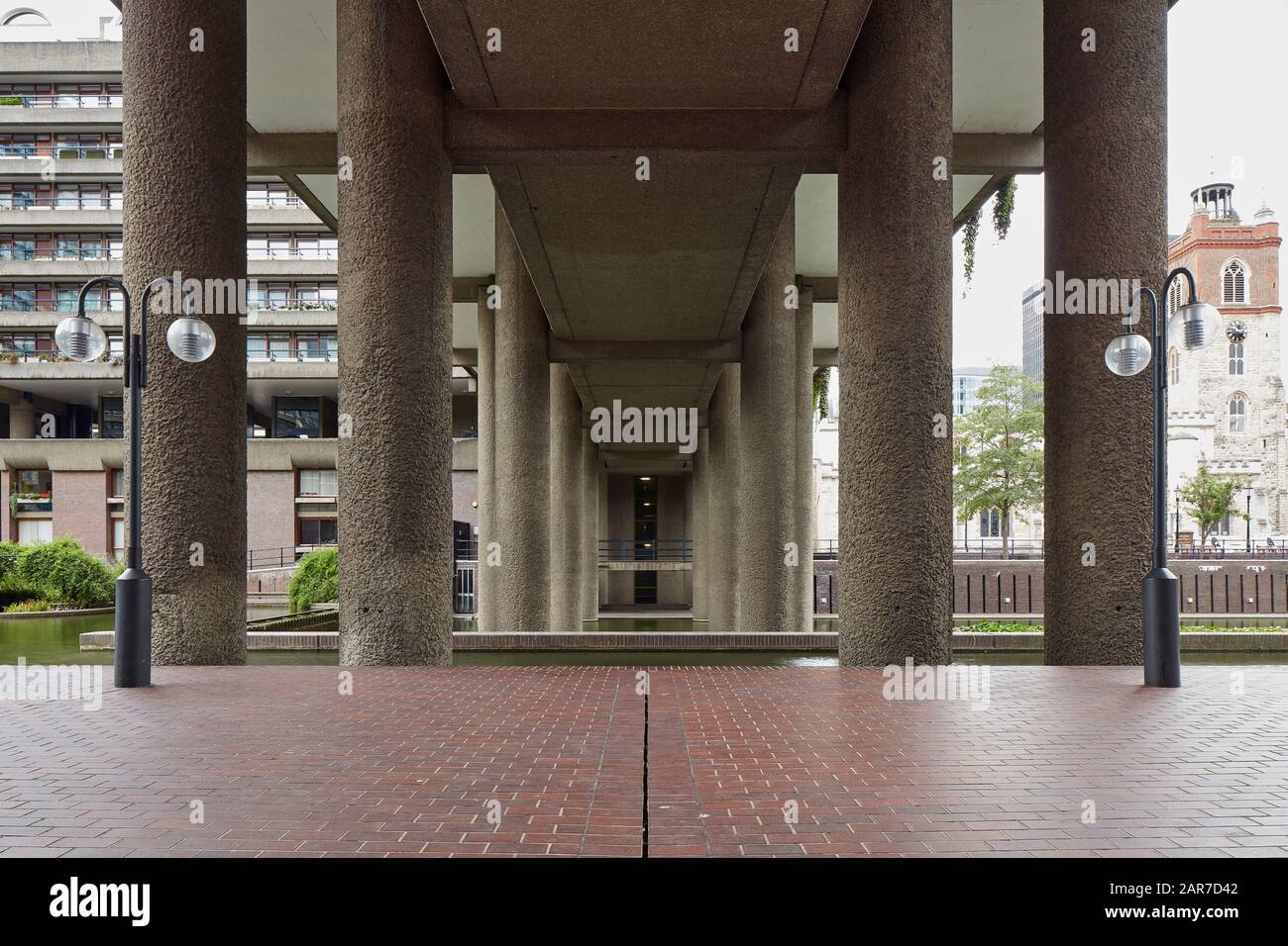 View through load-bearing colonnade with water features. Barbican Estate, London, United Kingdom. Architect: Chamberlin, Powell and Bon, 1969. Stock Photo