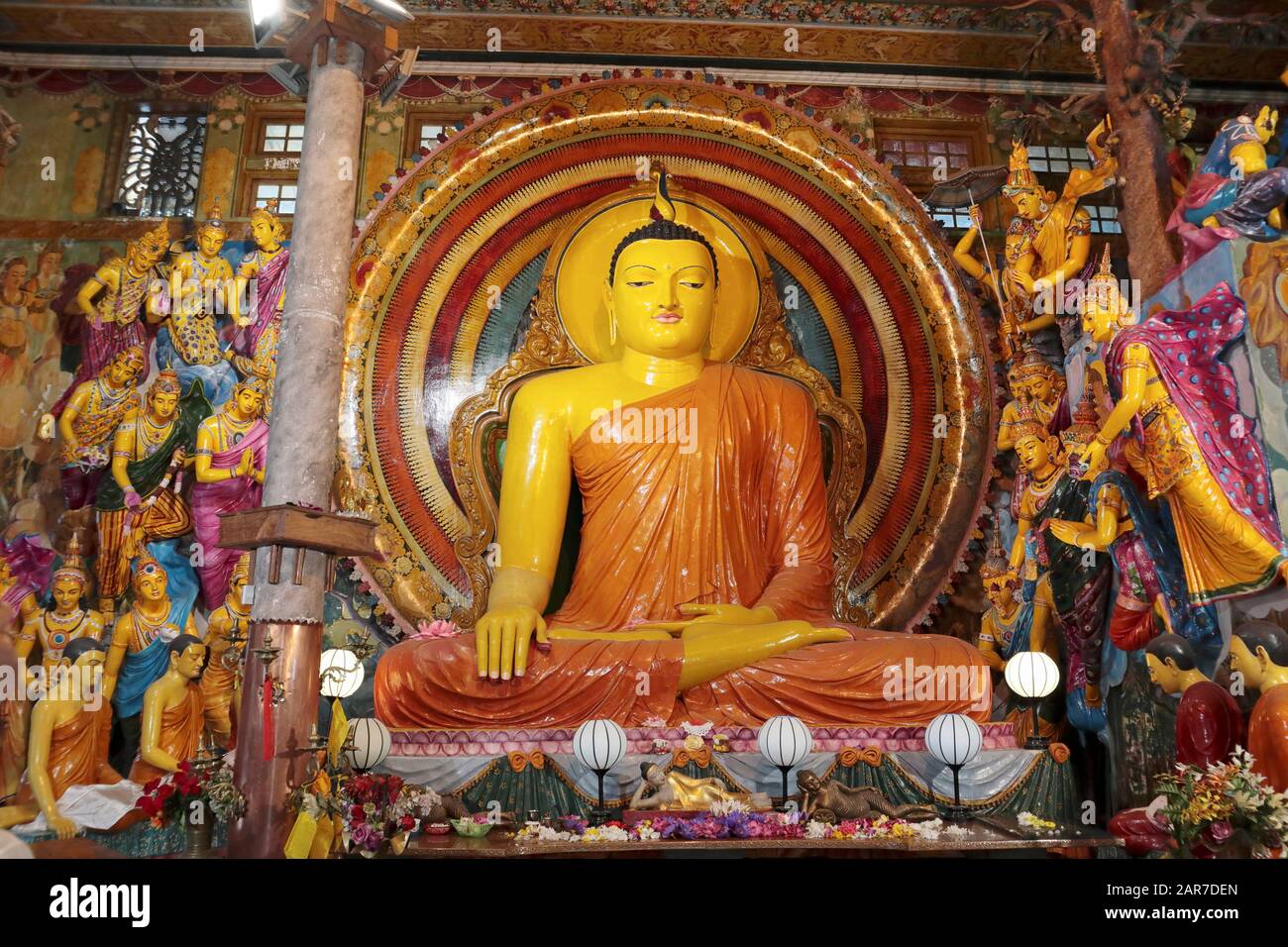 Brightly coloured figures flanking a large seated buddha statue in the Gangaramaya Temple, Colombo, Sri Lanka Stock Photo