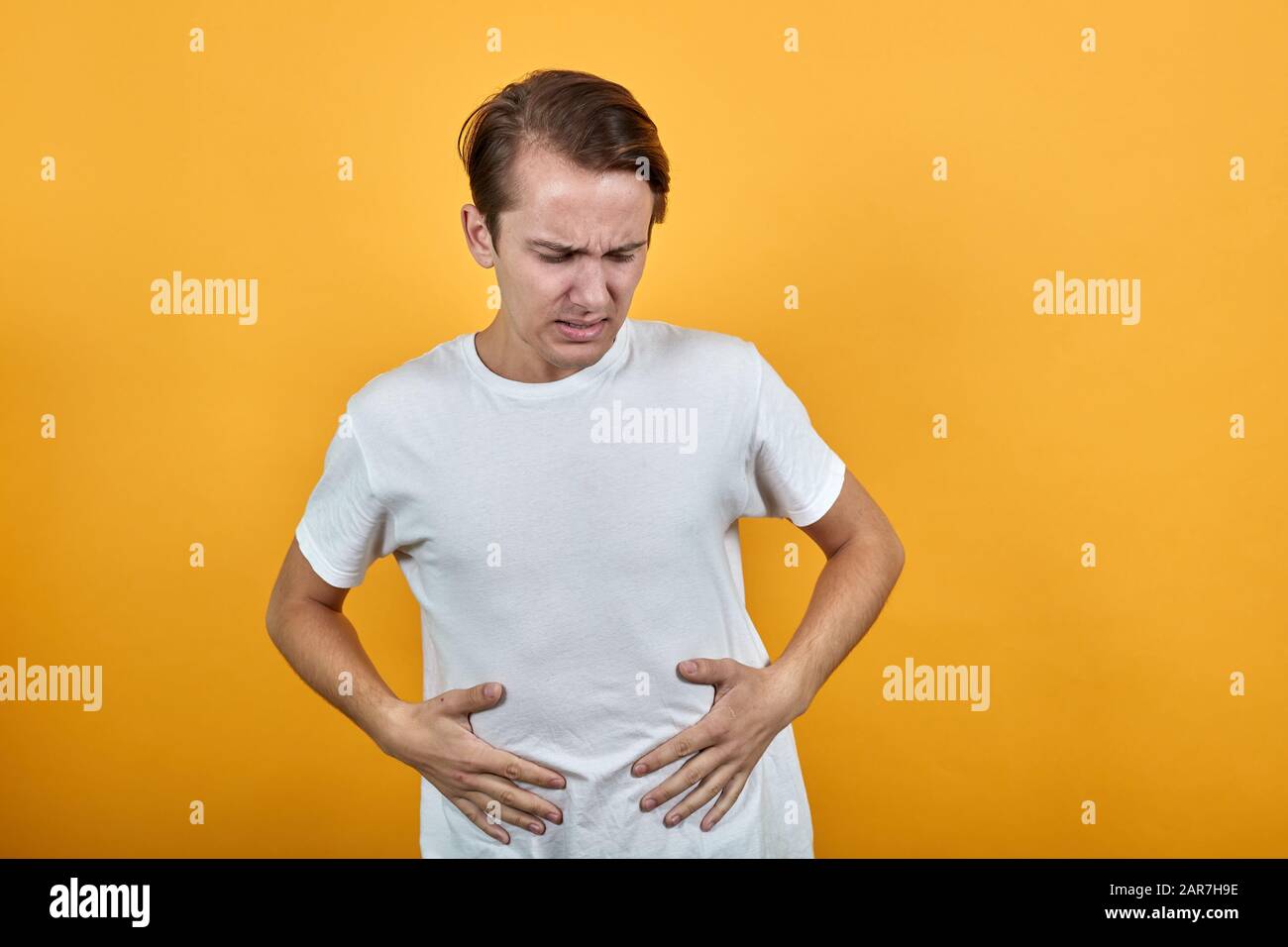 Man in white tshirt diarrhea health problems on yellow background