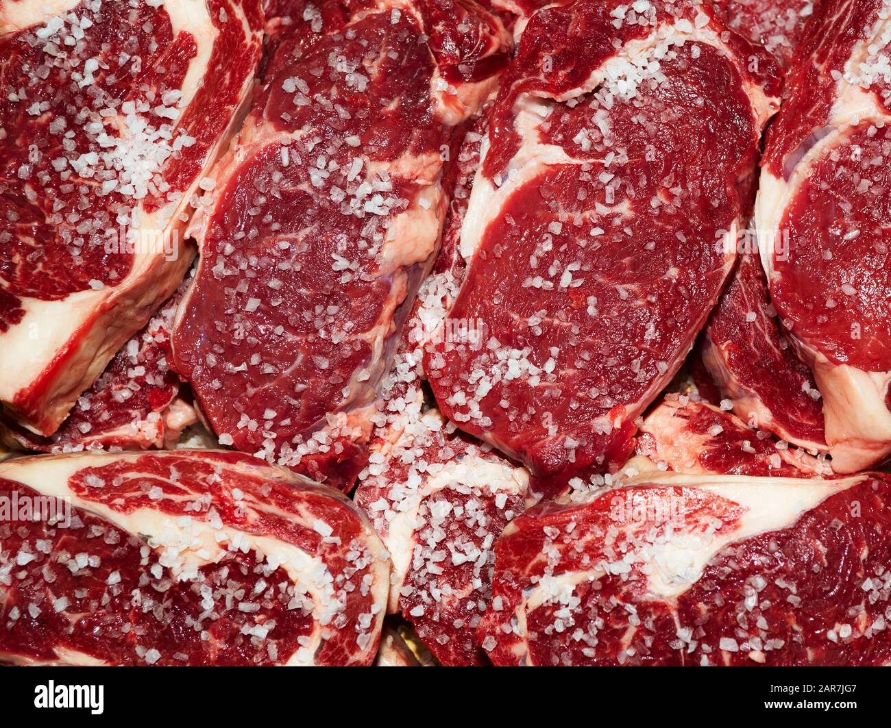 Fresh raw beef steak with salt on wooden cutting board, top view Stock Photo