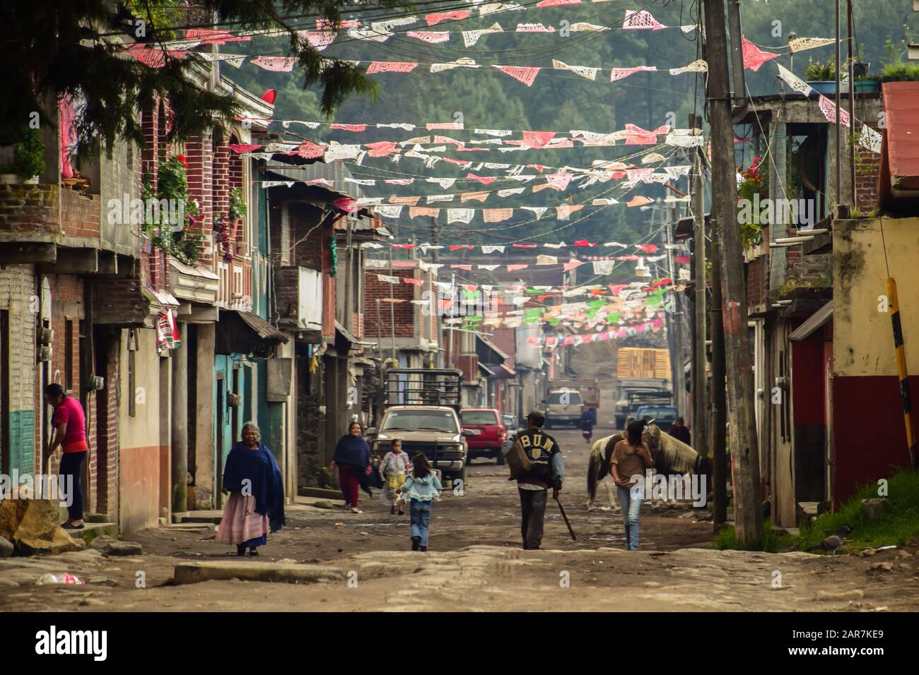 People walking down a dusty street beneath bunting flags, Paricutin, Mexico Stock Photo