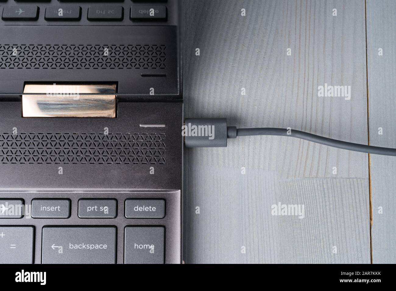 USB Type C grey cable connected to the laptop computer. Flat lay top view. Stock Photo