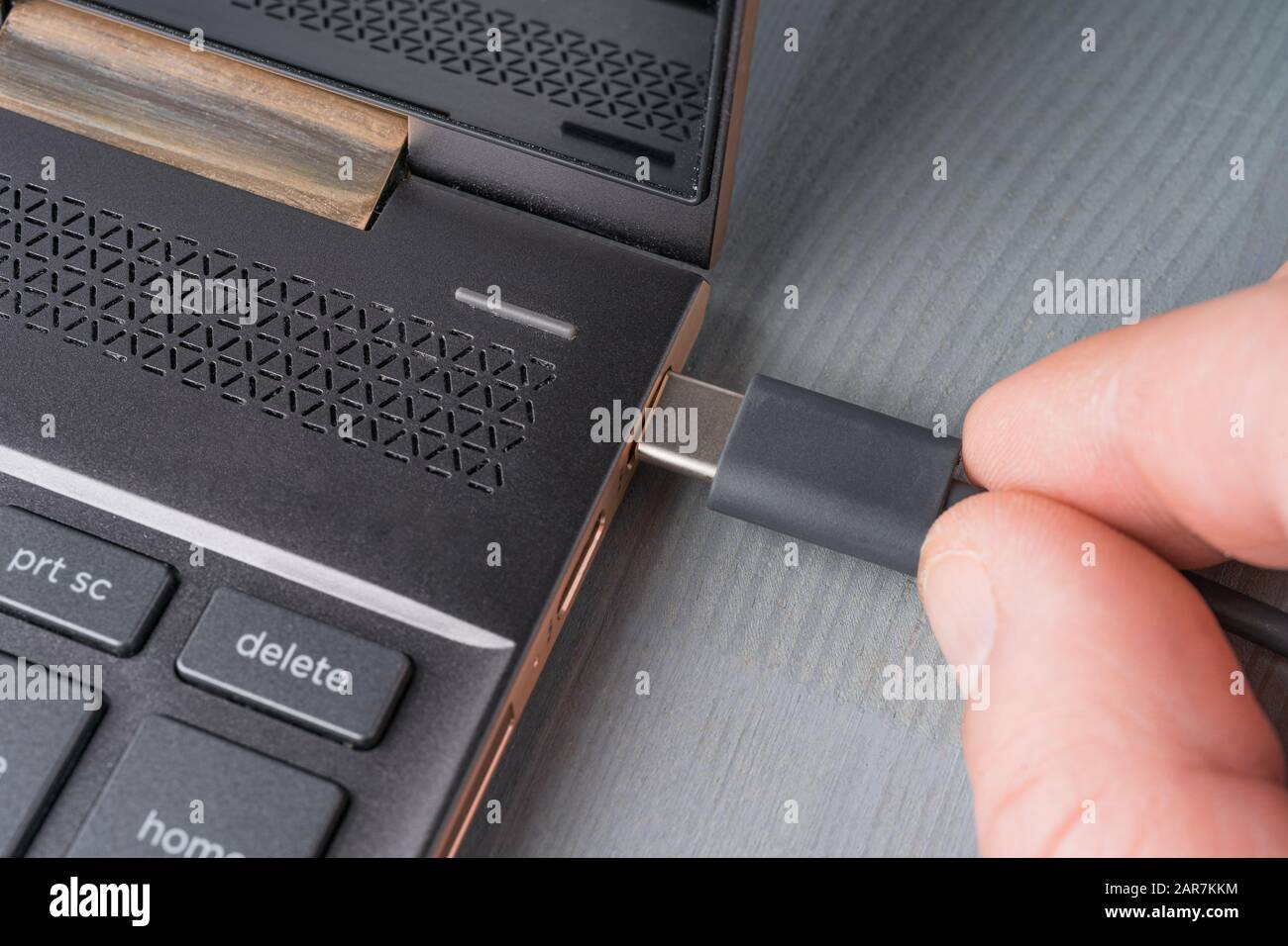 Closeup of USB Type C grey cable being connected to the laptop computer. Stock Photo