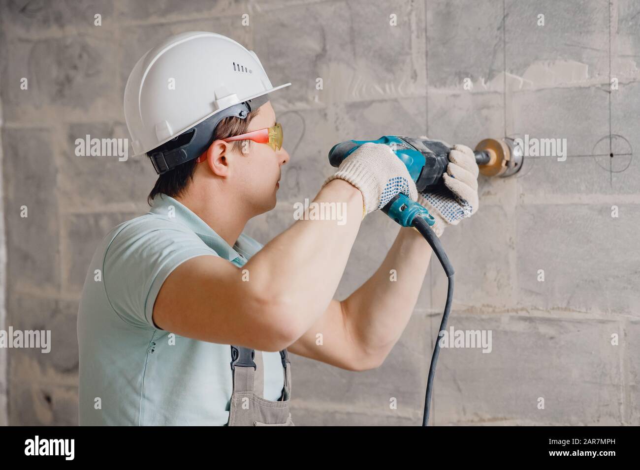 Builder worker pneumatic hammer drills hole in concrete brick wall with