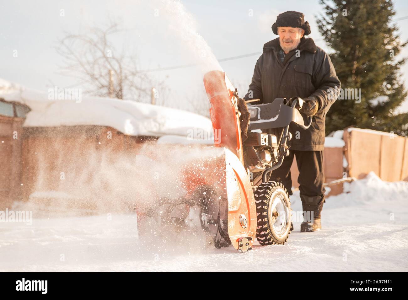Man cleaning snow from thrower blower machine removal ice storm winter