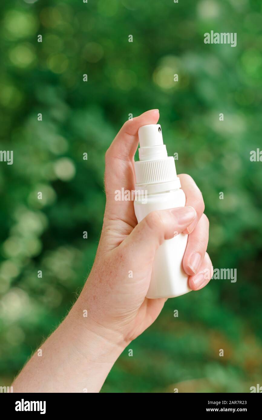 Woman using antiseptic spray outdoors in forest to protect the injury