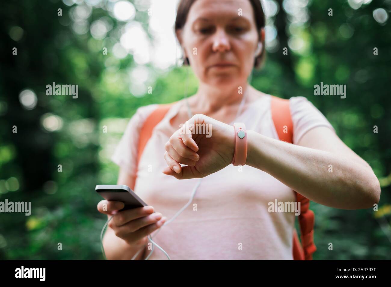 Female hiker checking fitness tracker wristband data and synchronizing