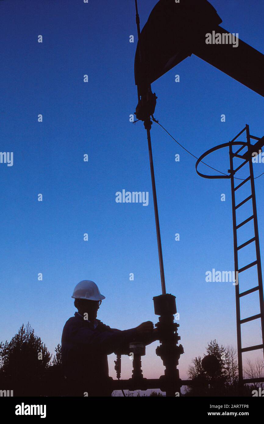 Oil and gas technician maintaining a pumpjack at an oil field Stock