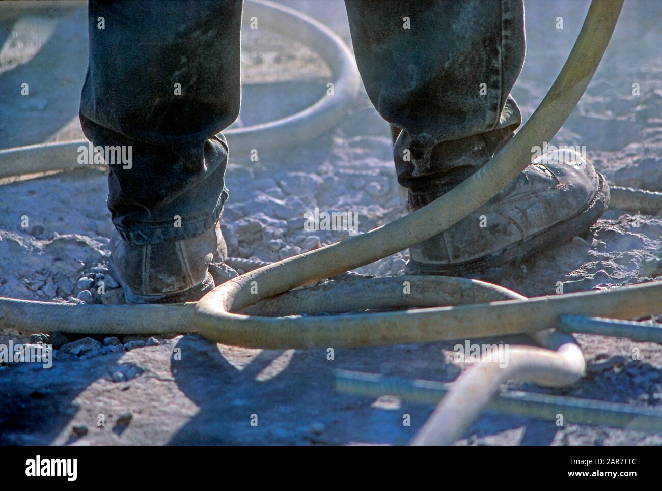 Construction worker's boots while using a jackhammer Stock Photo