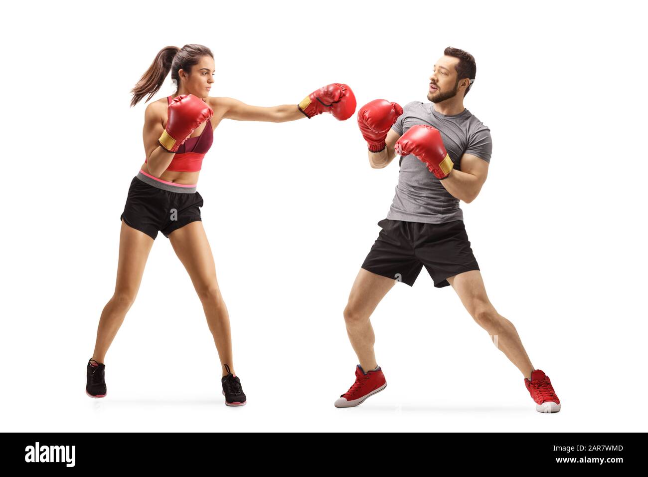 Full length shot of a young woman punching a man with boxing gloves isolated on white background Stock Photo