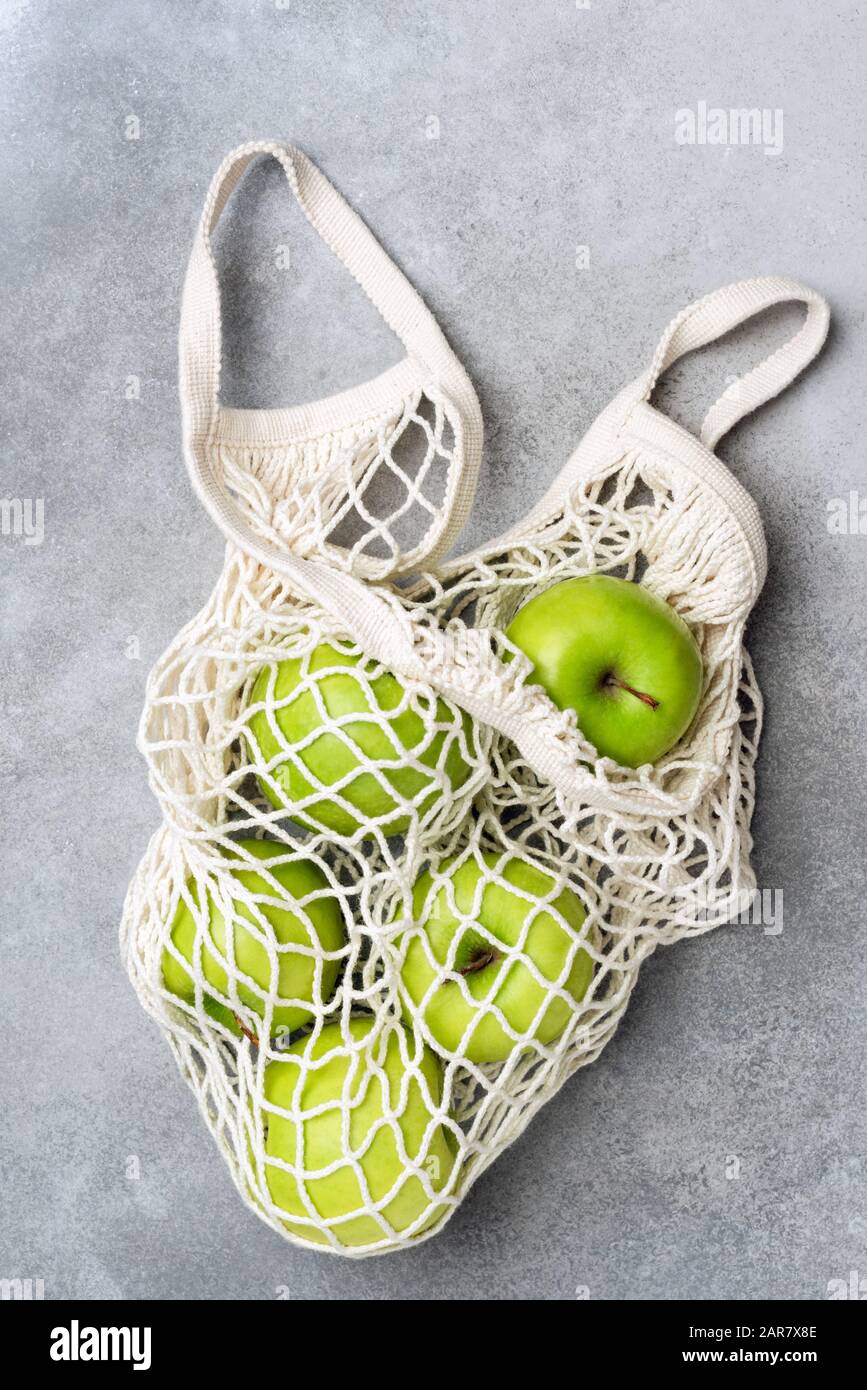 Mesh shopping bag with green apples on grey concrete background. Top view. Zero waste concept, healthy eco friendly lifestyle concept Stock Photo