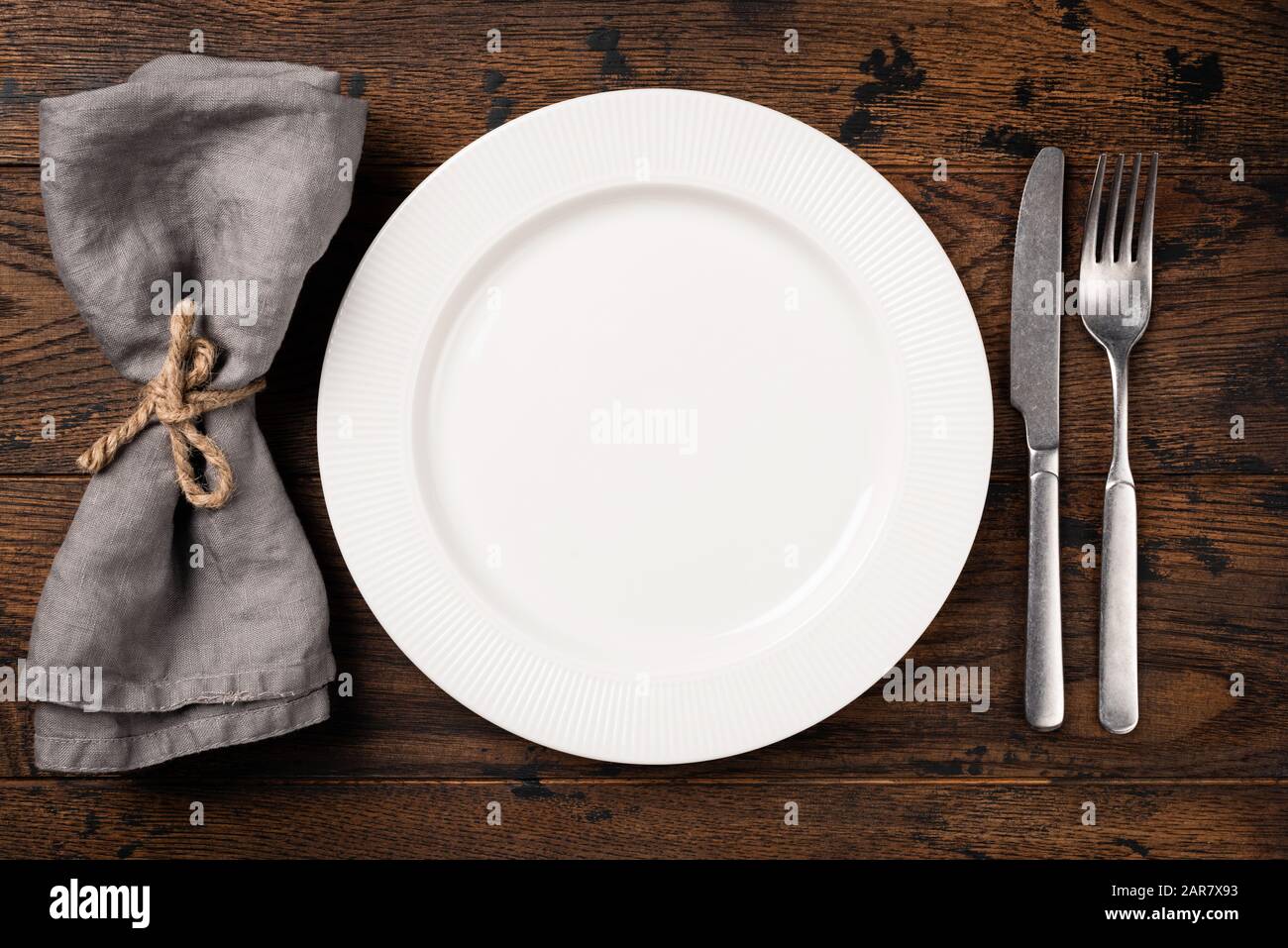 Table setting with empty white plate, cutlery and table napkin. Top view, copy space for text. Dinner table Stock Photo