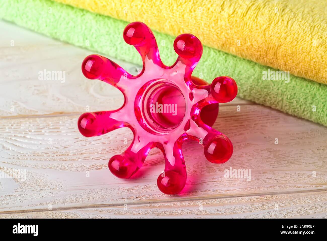Plastic spa massager in the form of an octopus on a white wooden surface. Massage handheld tool for limbs and body. Front. view. Stock Photo