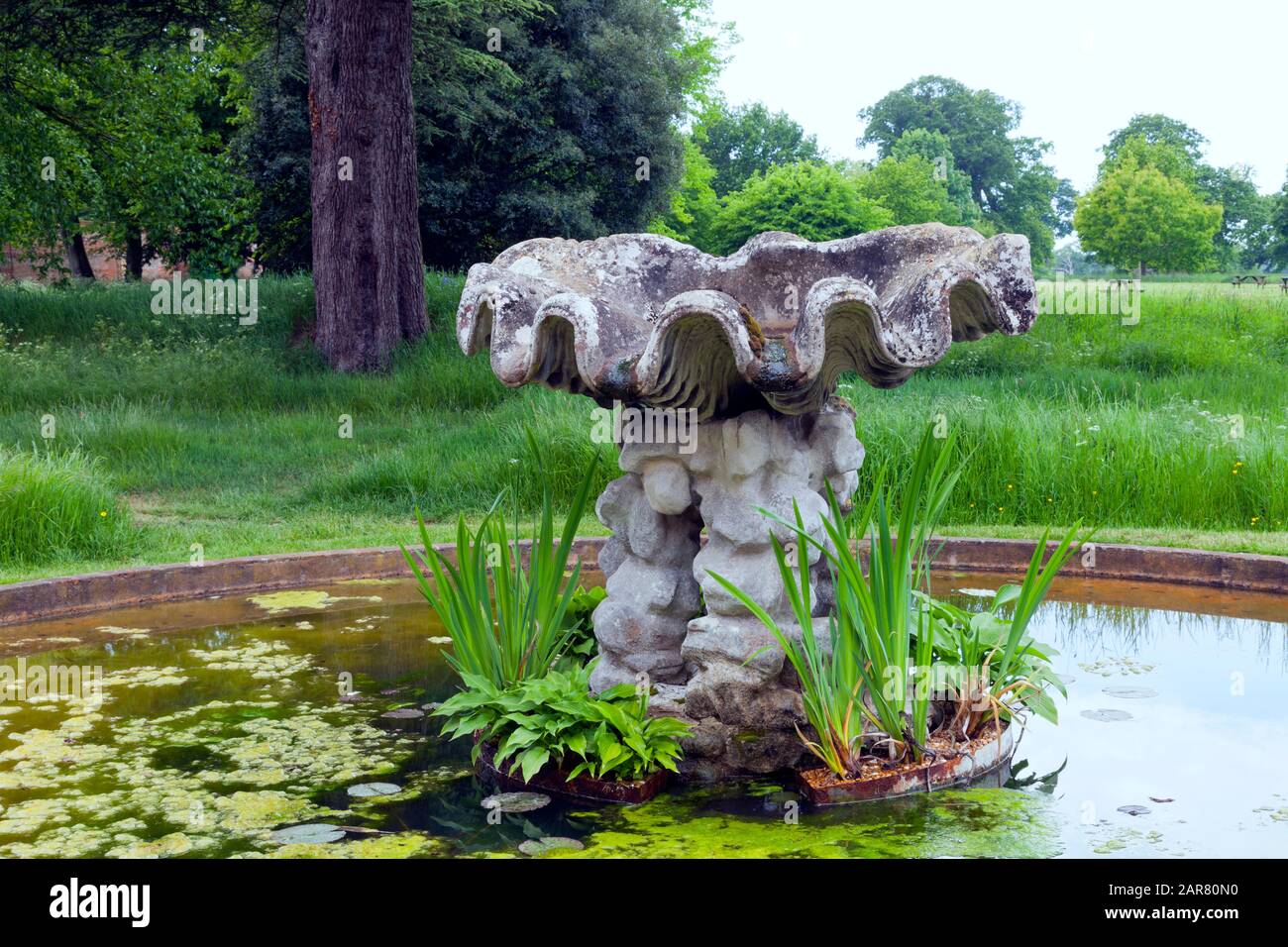 Stone water feature in a garden pond on the edge of rural English countryside, Cotswolds, UK . Stock Photo