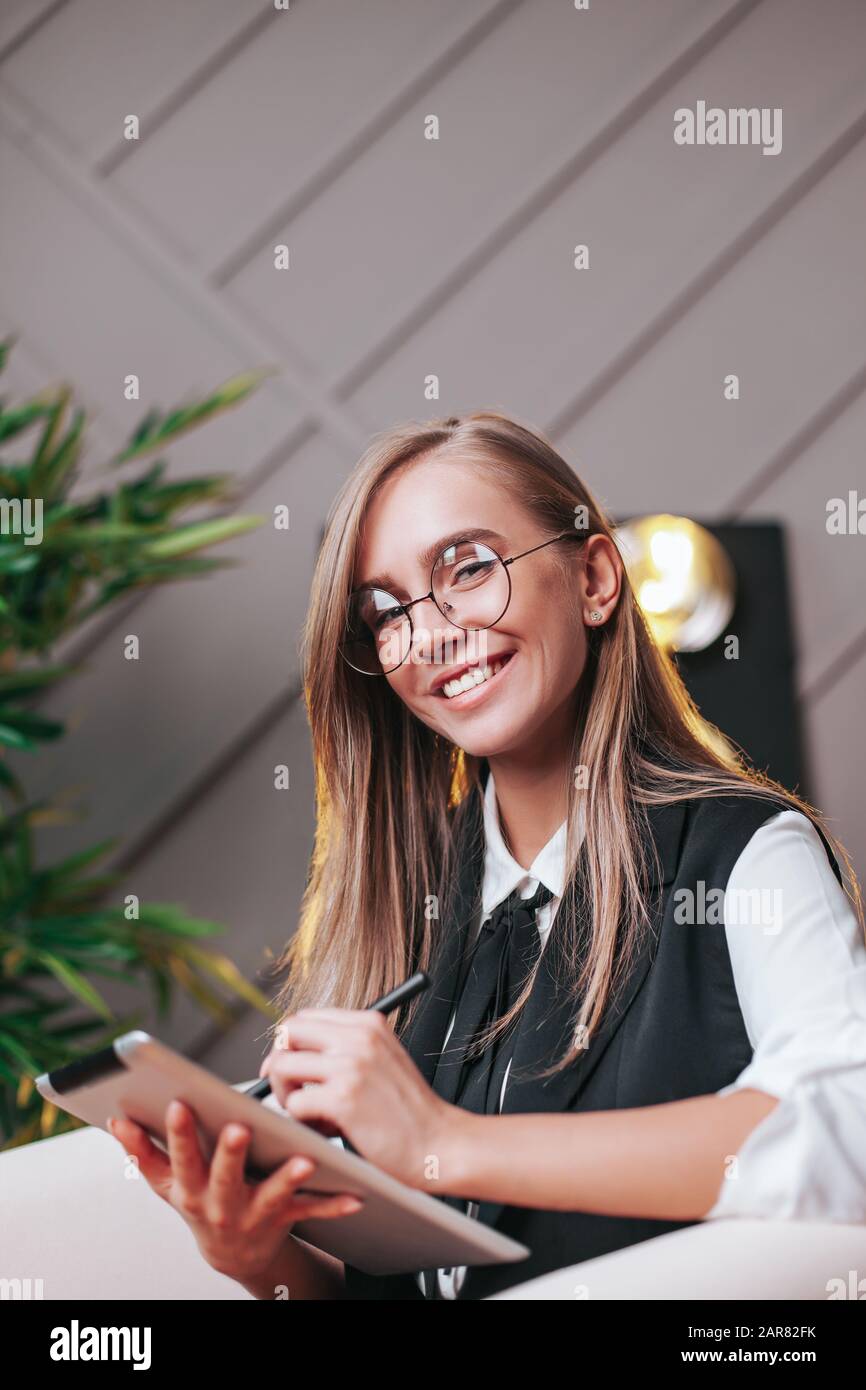 Beauty young woman in glasses siting in the office with tablet, generating ideas. Plants on the background. Business and education Stock Photo