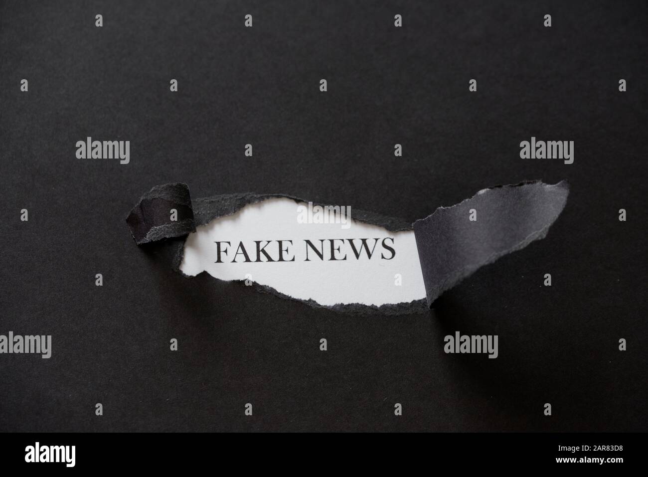 Fake news printed on a white background with black torn paper. Fake Stock Photo