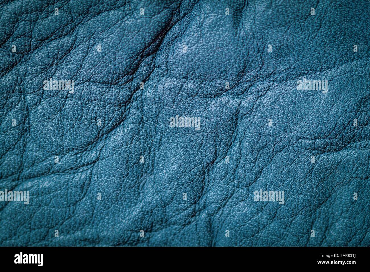 Texture of genuine leather close-up, surface close-up with wrinkles and cracks, blue color print, trendy background. Copy space Stock Photo