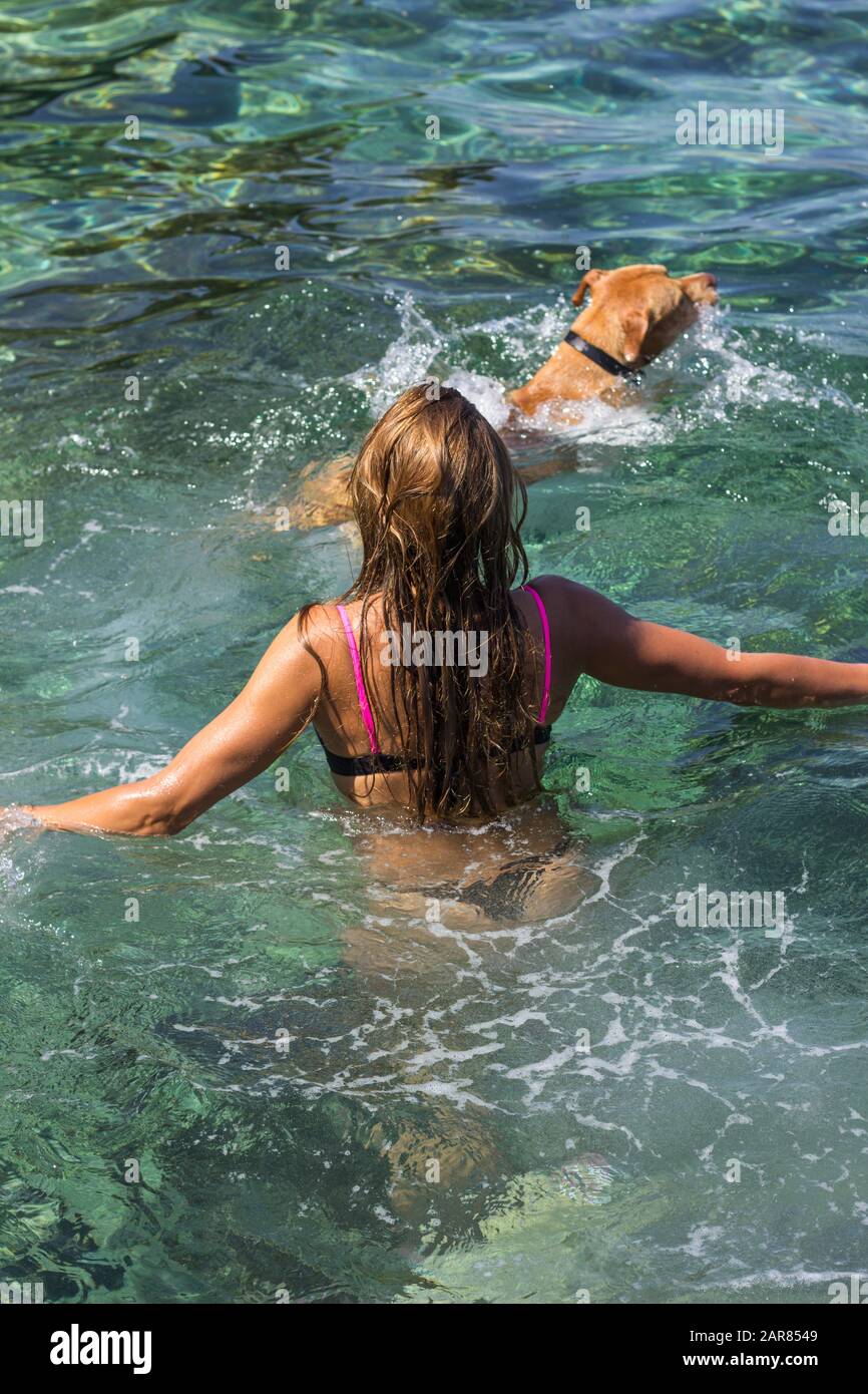 Young woman swimming with her dog at sea lagoon Stock Photo