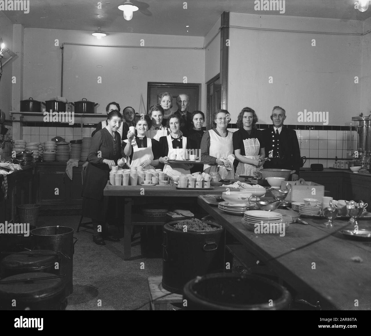 On the occasion of the reception of 120 French students in our country after arrival a simple dinner offered by the municipality of Amsterdam in the City Hall. The kitchen staff poses with Mr. P.J. Mijksenaar, chief of the Municipal Press and Propaganda Service Date: 22 March 1946 Location: Amsterdam Keywords: group portraits, kitchens, employees Personal name: Mijksenaar, P.J. Stock Photo