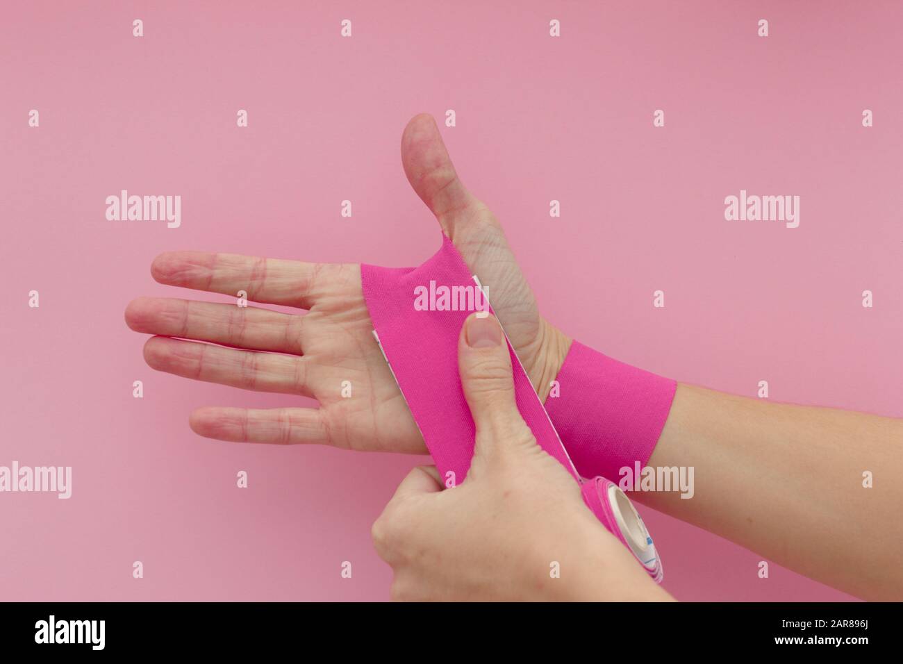 Appling a kinesio tape to hand isolated on pink background. Physiotherapy  tape for wrist pain, aches and tension. elastic therapeutic tape. adhesive  Stock Photo - Alamy