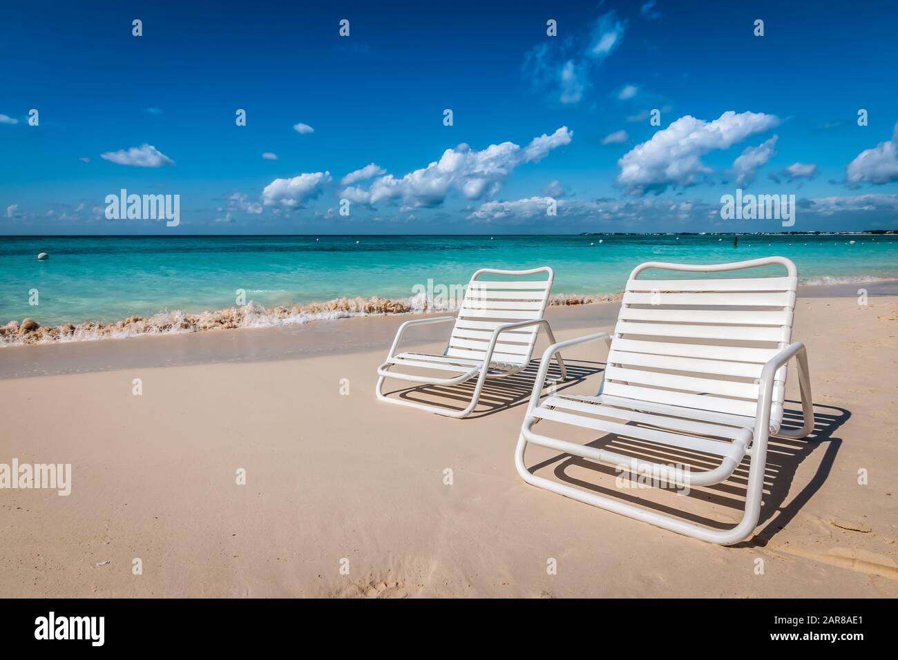 Two white beach chairs on Seven Mile Beach in Grand Cayman, Cayman Islands. Stock Photo