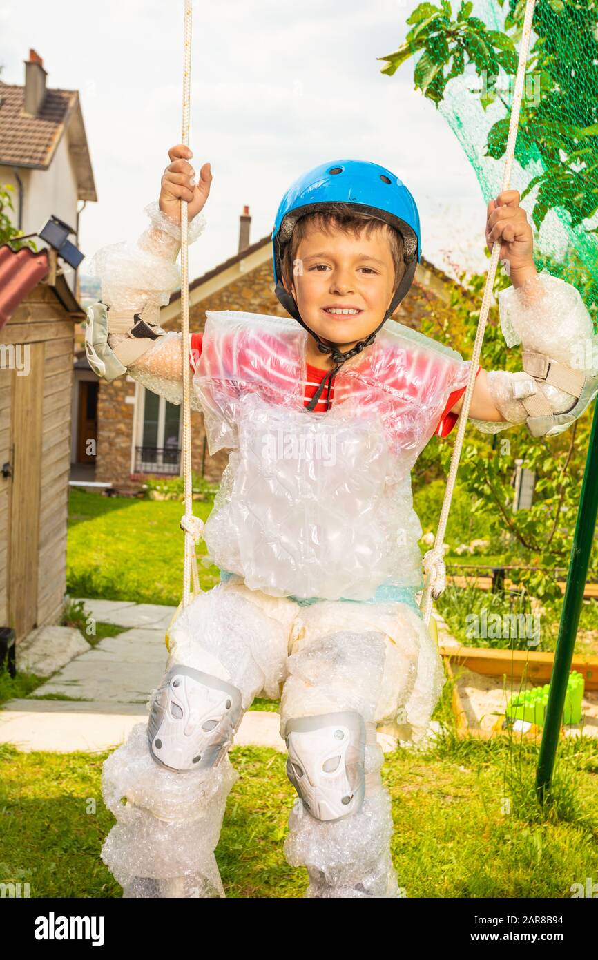 Close portrait of a super safe boy kid in bubble wrap and helmet swing