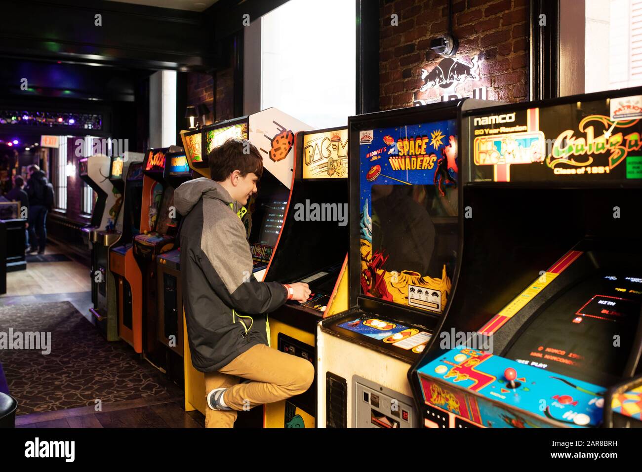 A sixteen-year-old boy plays Pac-Man at Versus, an arcade and bar on Province Street in Boston, Massachusetts, USA. Stock Photo