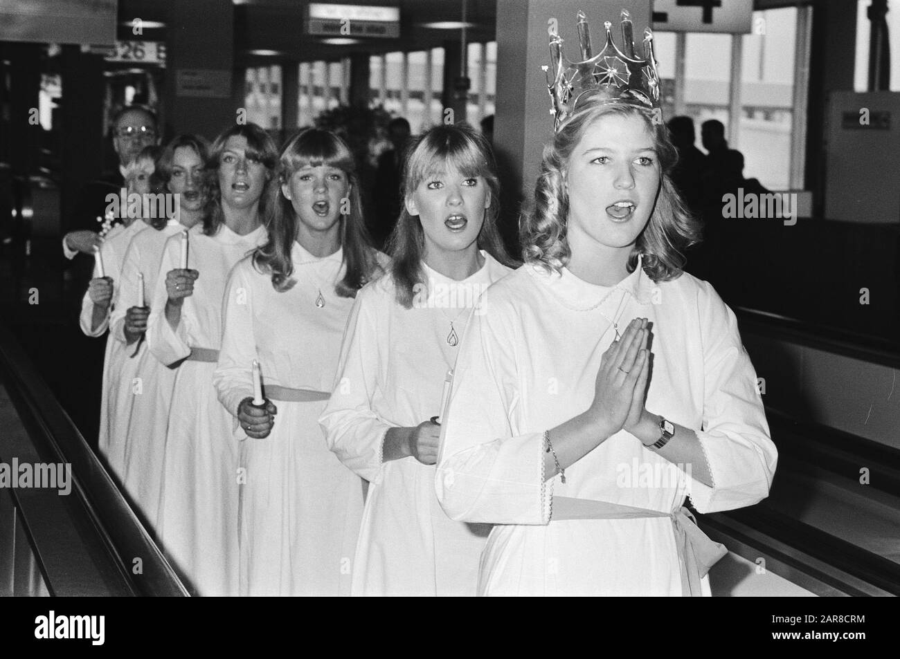 Swedish Lucia arrives at Schiphol with her retinue  Saint Lucia, adorned with a crown and her retinue on the treadmill Date: 13 December 1982 Location: Noord-Holland, Schiphol Keywords: arrivals, saints, religious holidays Personal name: LUCIA Stock Photo