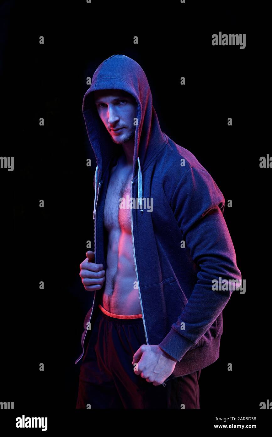 Young male muscular athlete in unzipped hoodie standing in front of camera Stock Photo